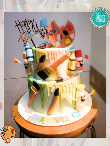 A cake that is a true work of art, for an artist. This two-tiered cake is decorated with edible paintbrushes, a color palette, and colorful drips to look like a creative masterpiece.