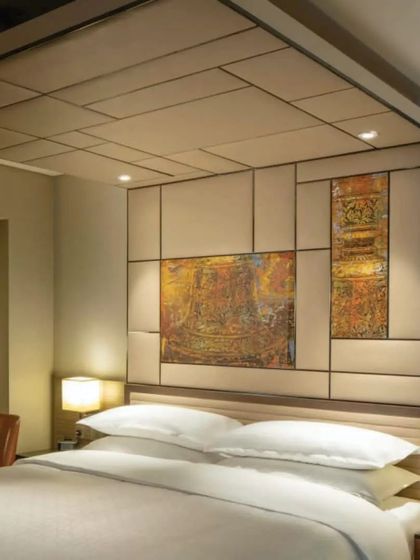 A masterfully integrated artwork above the headboard in a Master Room at the Sheraton Grand. This piece subtly incorporates architectural elements from Karnataka's heritage, including the Mysore Palace and Badami pillars.
