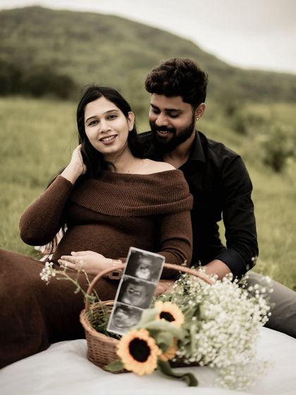 A lovely picnic scene, with the couple sitting together and looking at the sonogram pictures. The basket of flowers adds a beautiful touch of color.