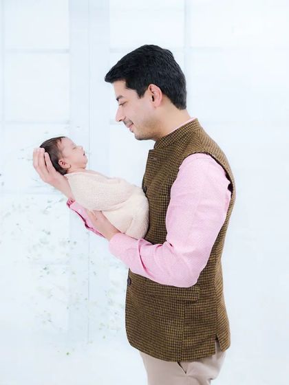 A new father gazes lovingly at his newborn, holding the baby carefully in his hands. A powerful image showcasing a father's gentle love.