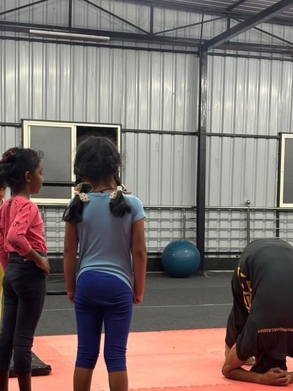 A student practices his tripod headstand, a foundational move for building neck and shoulder strength.