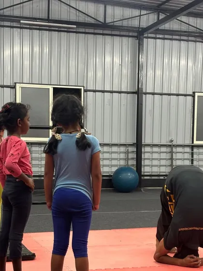 A student practices his tripod headstand, a foundational move for building neck and shoulder strength.