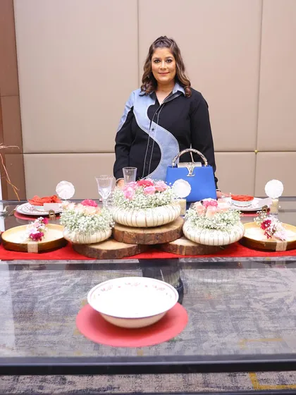 Standing proudly with the tablescape created during my workshop with Trovea's. I love teaching others how to combine elements like floral arrangements, wooden platters, and elegant dinnerware.