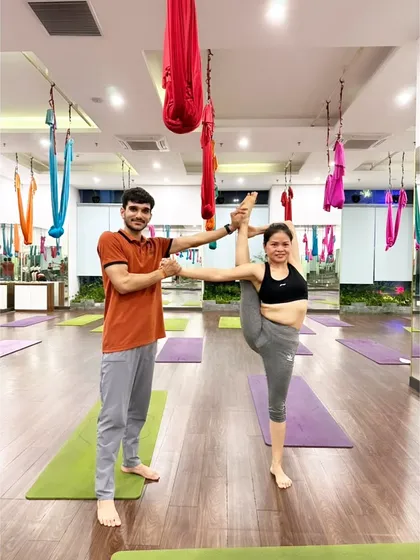 In a studio in Vietnam, assisting a student with the Flag Pose. This demonstrates my international teaching experience and ability to work with advanced practitioners.