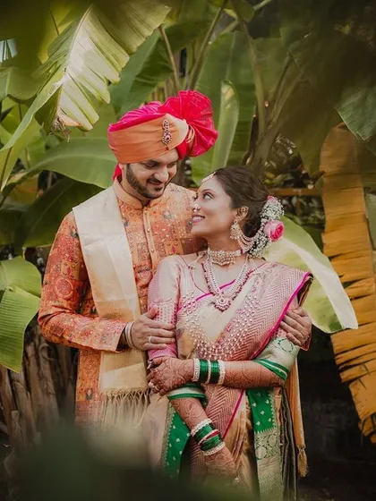 A beautiful portrait of a Maharashtrian couple standing together. The bride's elegant Paithani saree and the groom's coordinated attire create a timeless image of their wedding day.