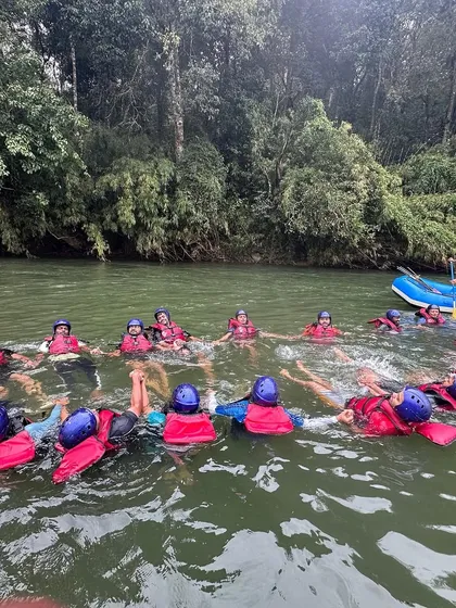 A group of rafters forms a floating circle, holding hands in the calm river. This is a classic team-bonding activity that builds trust and friendship.