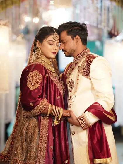 An intimate portrait of a couple in rich maroon and cream wedding attire, capturing a quiet moment together.