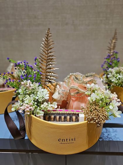 For Entisi Chocolatier, I curated these elegant oval hampers. The design combines their chocolate boxes with delicate floral arrangements, golden ferns, and organza potlis, creating a very pretty and high-end presentation.