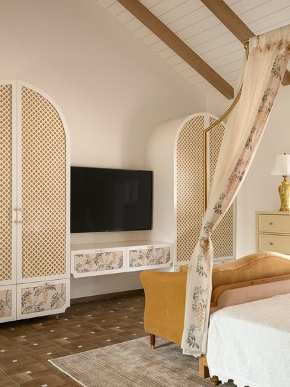 The media and storage unit in the Verdant Manor bedroom was custom-designed with arched, latticed doors and floral panel inlays, echoing the romantic, old-world charm of the space.