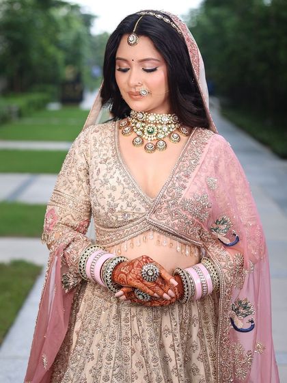 A close-up of the bride's serene expression. The detailed jewelry and the soft colors of the lehenga come together for a picture-perfect moment.