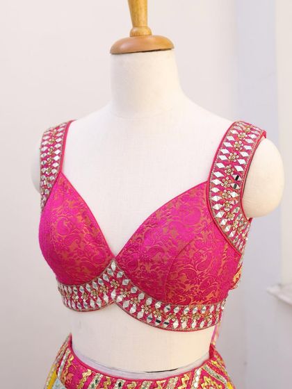 A close-up of the hot pink blouse with mirror work. The intricate detailing and vibrant color make it a standout piece.