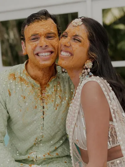 A sweet and candid moment of the couple, their faces glowing with turmeric and happiness.