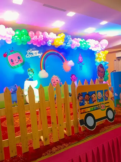 A colorful Cocomelon-themed birthday stage with a picket fence prop.