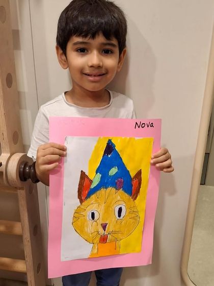 Another student proudly presents his finished piece. Even when learning the same subject, each child's artwork is a unique expression of their personality.