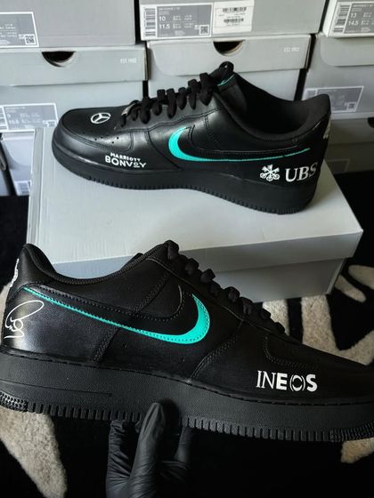 A sleek pair of black Nike Air Force 1s customized with the Mercedes-AMG F1 team livery and Lewis Hamilton's signature.