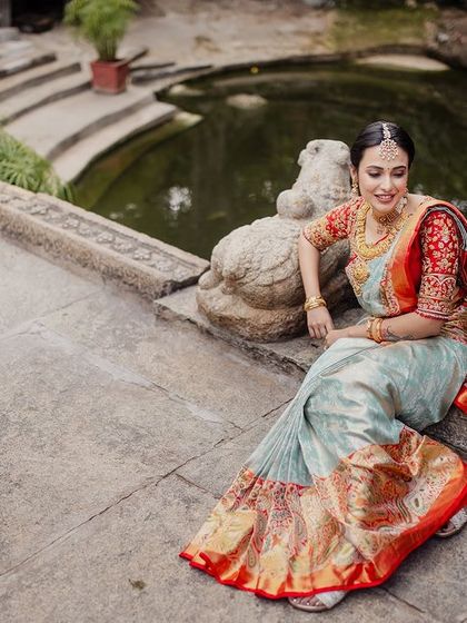 A bride sits on the steps of the kalyani, her beautiful saree spread out, creating a graceful and serene image.
