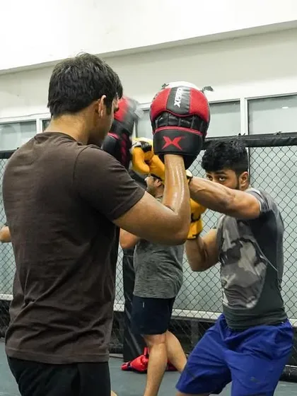 A student works on their punching combinations with a coach holding pads. Pad work is essential for developing speed, accuracy, and power.