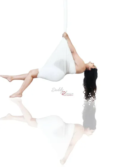An artistic and creative studio shot featuring a suspended pose with a perfect reflection. This demonstrates the unique, gravity-defying concepts I can create for a truly memorable and artistic pregnancy photoshoot.