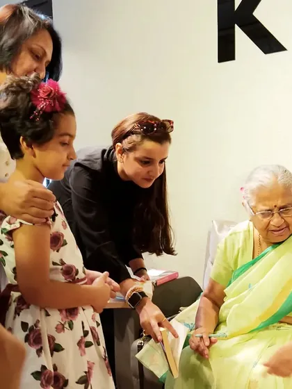 A young girl and her mother watch as Sudha Murty signs their book. These events are wonderful family experiences, creating lasting memories centered around books.