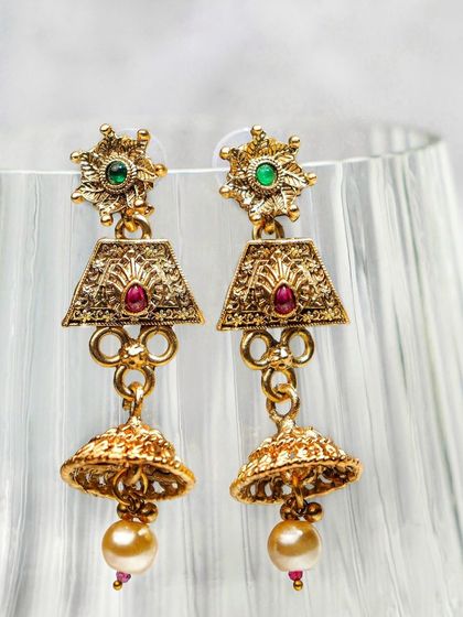 Traditional jhumka earrings styled against a fluted glass, using light and shadow to create an elegant mood. This creative approach elevates a standard product shot.