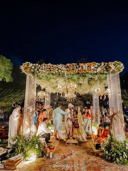 A wide shot of the beautiful outdoor ceremony in Udaipur, with the mandap set against a cascading waterfall.