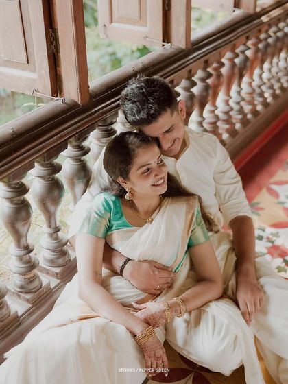 A tender moment shared on the veranda of a traditional house, the couple looking at each other with love.