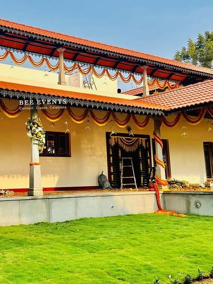 A full view of a traditional farmhouse decorated for a housewarming ceremony. The marigold garlands tracing the roofline give the home a classic and celebratory look.