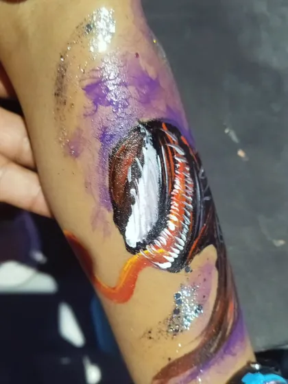 Another angle of the Venom arm tattoo, highlighting the texture and detail in the character's face and the shimmering glitter accents.