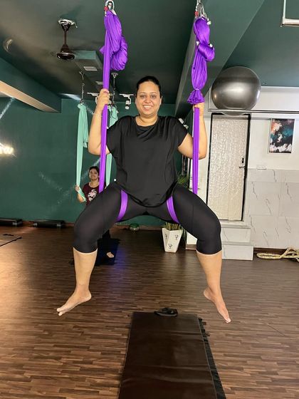 A joyful moment captured mid-air. This member is practicing a suspended wide-legged squat, which builds lower body strength and stability while enjoying the freedom of being off the ground.