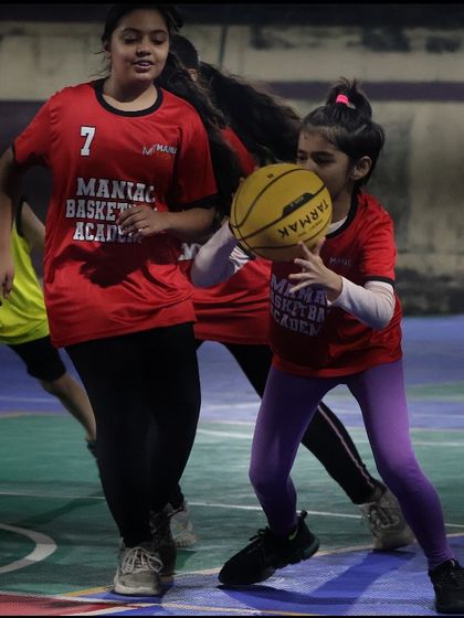 Two young girls compete for the ball, showing the competitive spirit we nurture. We teach our players to be tough but fair competitors.