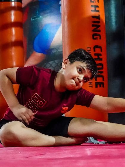 Flexibility is just as important as strength. This young member is working on his stretches, an essential part of our kids' MMA program that helps prevent injuries and improves performance.