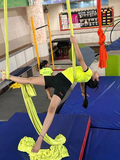 A young student holds a perfect split on the silks, a testament to her dedication and our progressive flexibility training.