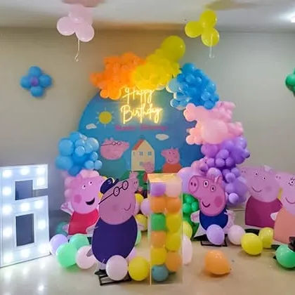A fun-filled Peppa Pig party setup with character cutouts, a colorful balloon arrangement, and a large "6" marquee number.