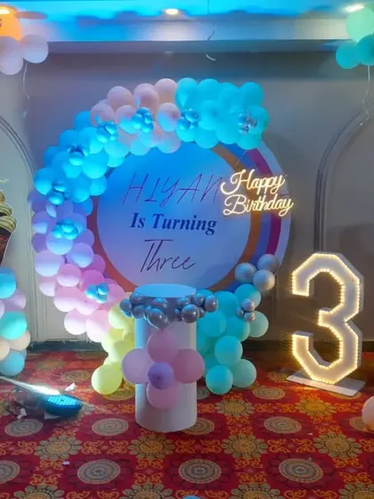 An ice cream theme for a 3rd birthday. This decoration includes a circular backdrop, ice cream cone balloon pillars, and a marquee number '3'.