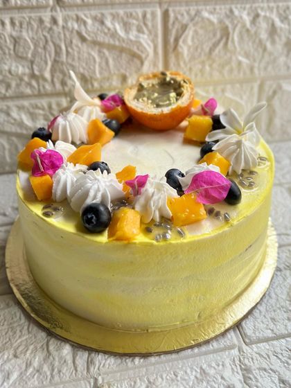 A side view of our Mango Passion Cake, showing the layers of creamy frosting and beautiful fruit decorations.