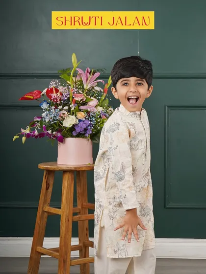 The joy on his face says it all. This little boy is having fun in his off-white printed kurta, a comfortable choice for a long day of festivities.