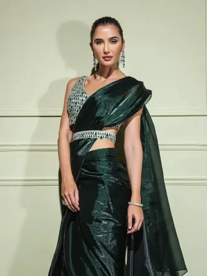 This emerald green organza saree has a beautiful metallic sheen. It's paired with a sequined blouse and a delicate, embellished belt to cinch the waist.