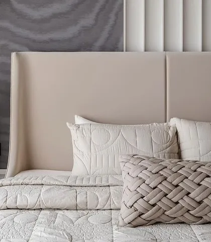 This modern bedroom demonstrates the power of texture. The wallcovering features a subtle, organic wave pattern that adds depth and a sensory quality, complementing the clean lines of the upholstered headboard and the intricate weave of the cushions.