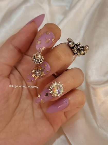 Another angle of the purple and gold Navratri nails, showing off the large crystal charm and the delicate placement of the gold accents.