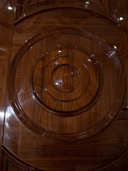 A detail shot of the circular molding on the high-gloss solid wood door, highlighting the depth and reflective quality of the polish.