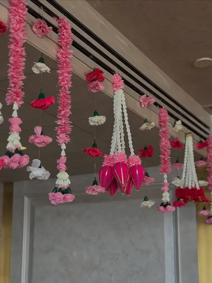 We created a breathtaking ceiling with hundreds of hanging floral strings (latkans) in shades of pink and white, transforming the room into a fragrant, festive canopy for a wedding celebration at home.