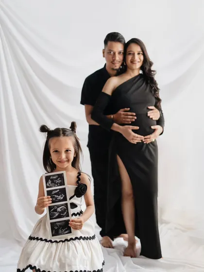 A creative and heartwarming way to announce a new arrival. This studio maternity portrait includes the excited big sister-to-be proudly holding the sonogram pictures, turning the session into a full family celebration.