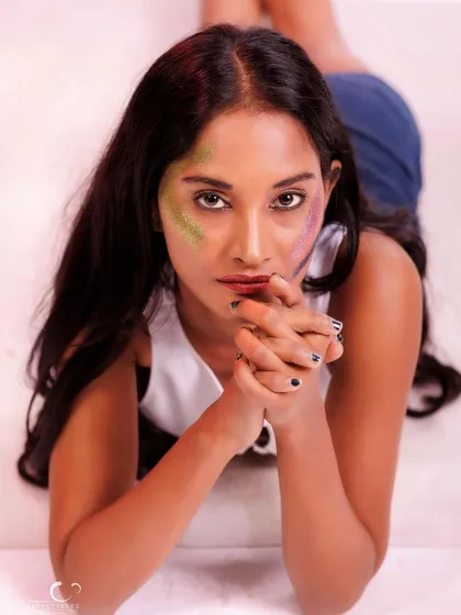 A direct and engaging portrait, showcasing the creative glitter makeup. Her expression is confident and captivating.