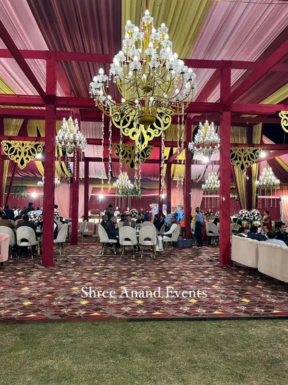 A wide view of the guest seating area, with tables and chairs spread across the lawn under a canopy of chandeliers.