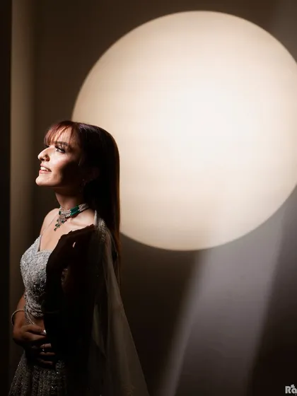 An artistic bridal portrait using a single, large light source to create a dramatic silhouette effect. The bride's upward gaze and smile convey a sense of hope and happiness.