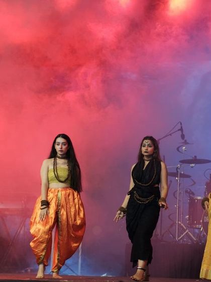 Models walking through red smoke on the runway at IIT Roorkee. This atmospheric shot highlights the creative production value of student-run fashion shows.
