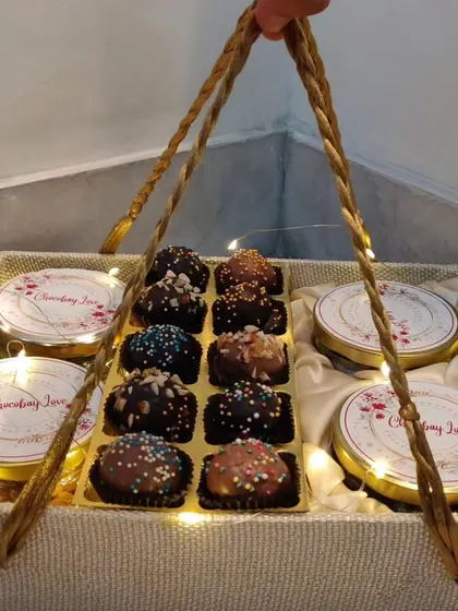 A beautiful fabric-covered basket filled with four tins of treats and a box of my signature chocolate truffles, illuminated by fairy lights.