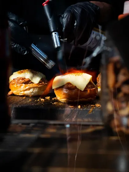 A dramatic shot of a blowtorch melting cheese over a bagel, with the flame creating an exciting visual that promises a warm, toasty, and delicious bite.