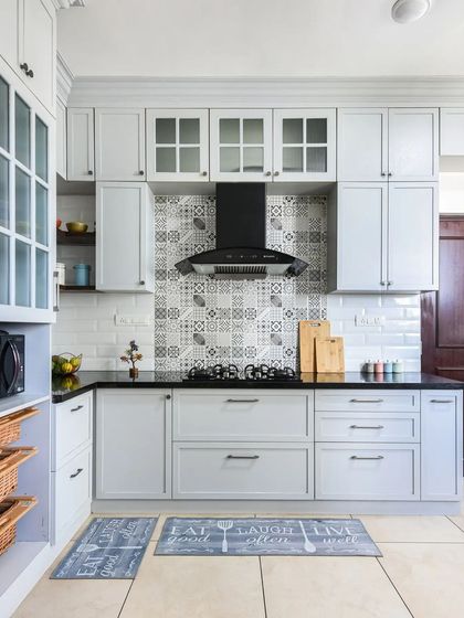 A full view of the classic grey kitchen, showing the shaker cabinets, patterned backsplash, and the clever bench seating nook under the window.