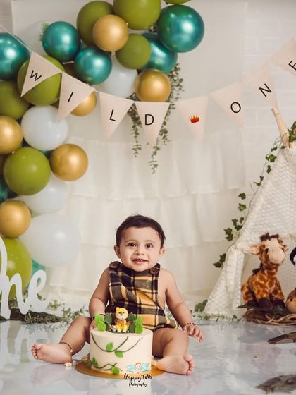 A "Wild One" cake smash is a popular choice for first birthdays. This jungle-themed setup includes a teepee, balloons, and a custom cake.